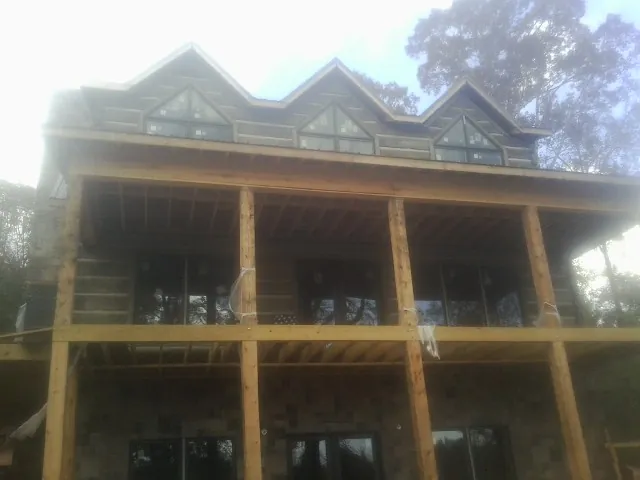 Dormers and porch framing on a large log home under construction — Roof Coating work by our crew in Lake Delton