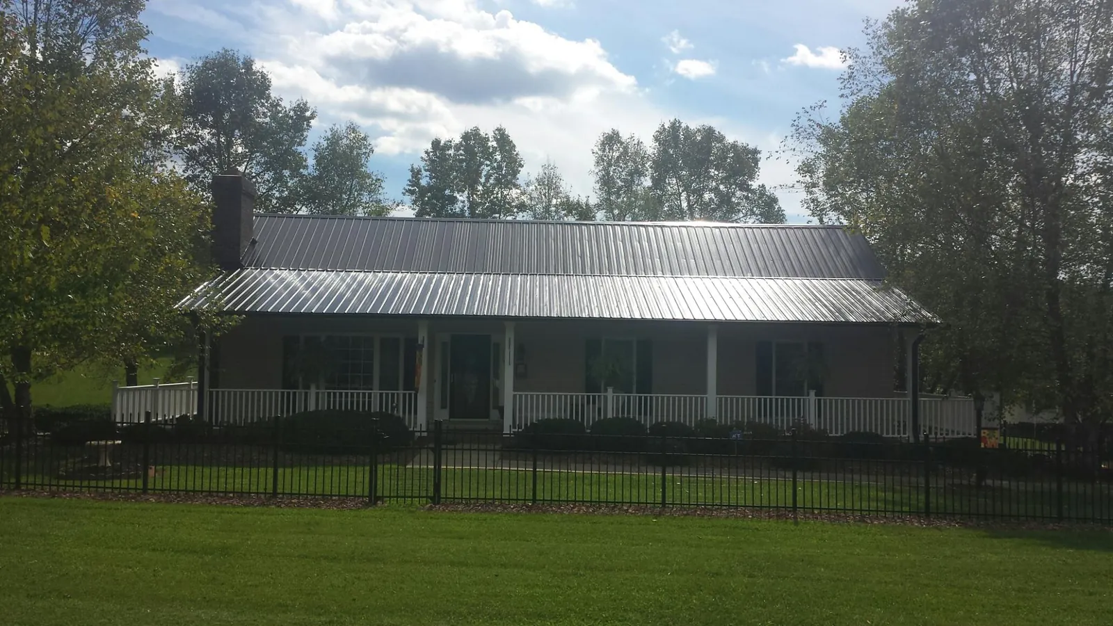 Gray metal roof on a brick ranch with a full width front porch — Gutter Guard Installation work by our crew in Lake Delton