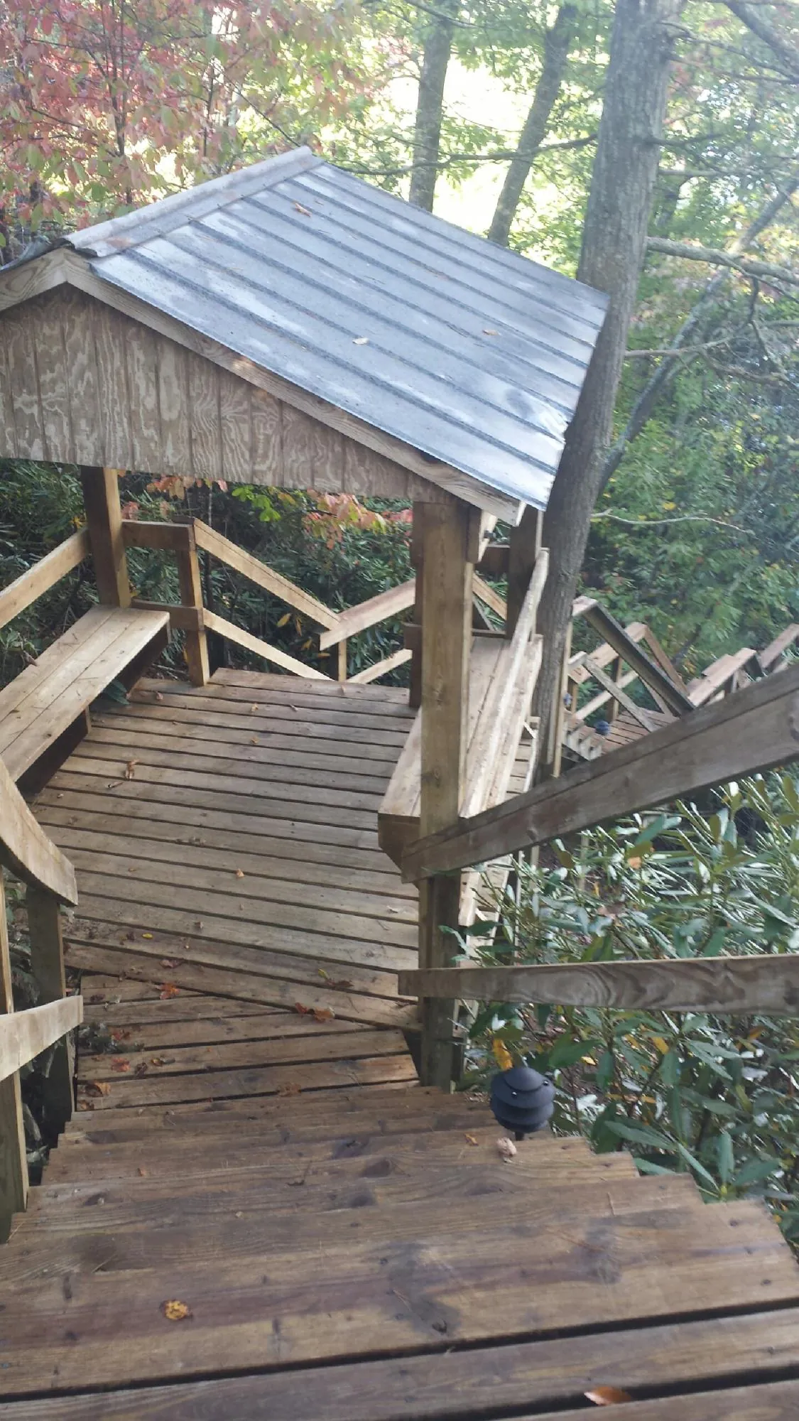 Metal roofed shelter over wooden steps on a wooded walkway — Skylight Repair & Installation work by our crew in Lake Delton
