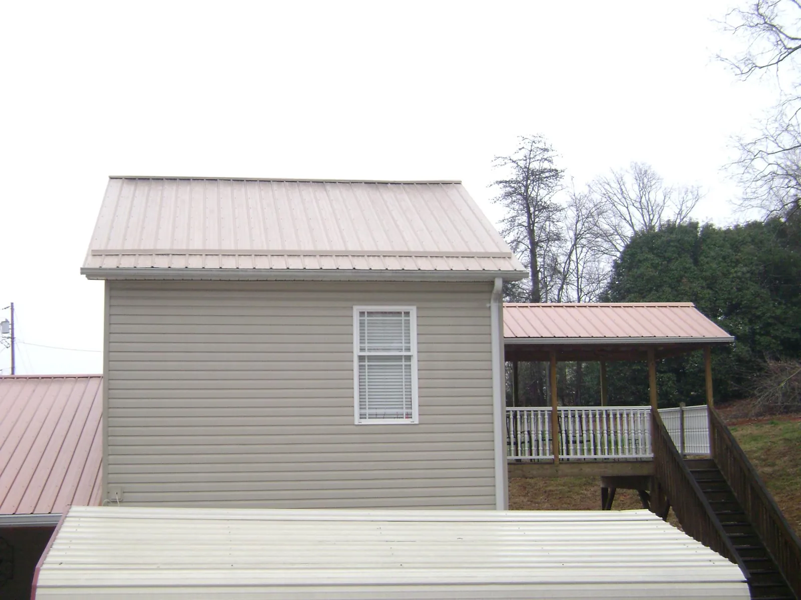 Tan metal roofs on a two story addition and attached porch, from a Roof Replacement job in Lake Delton