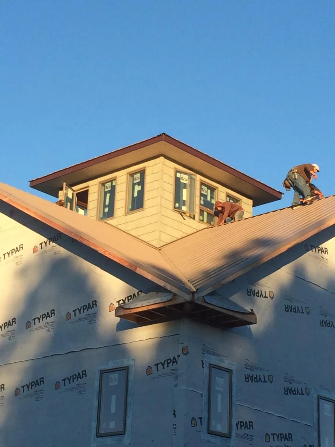 Roofers working around a rooftop cupola on a new metal roof at sunset — Roof Waterproofing in Lake Delton by Roofing Brothers
